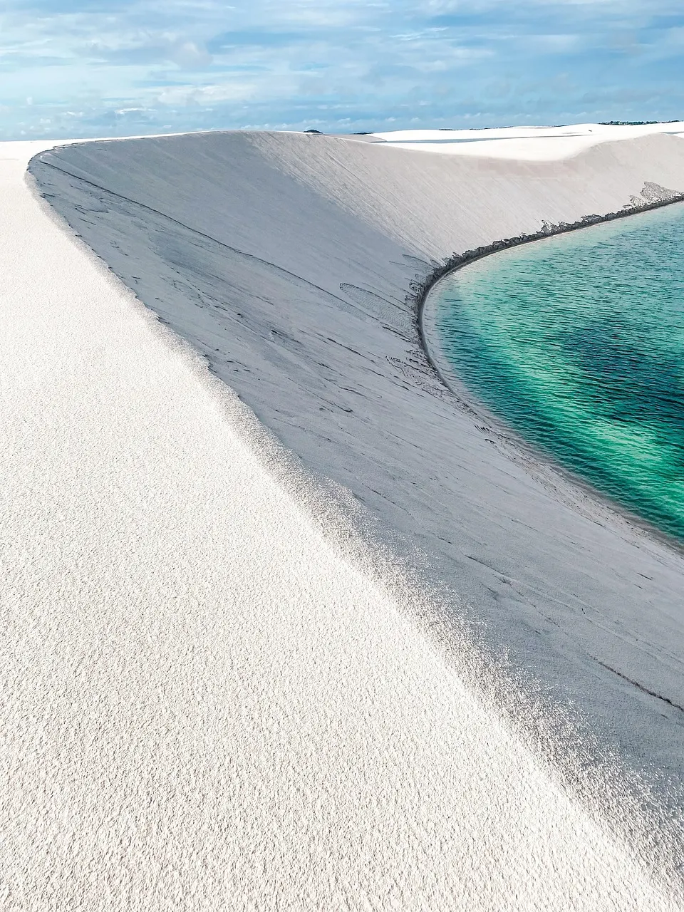 Licht zand dat in een boog langs turquoise water loopt in Marino Ballena National Park bij Uvita
