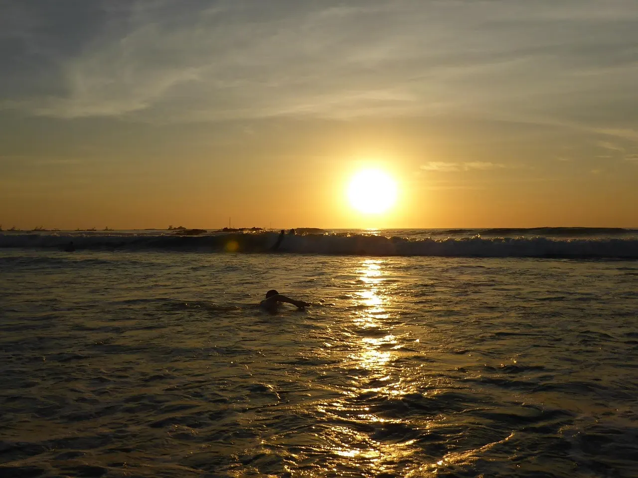 Zwemmer in zee bij zonsondergang boven de Stille Oceaan in de baai van Tamarindo